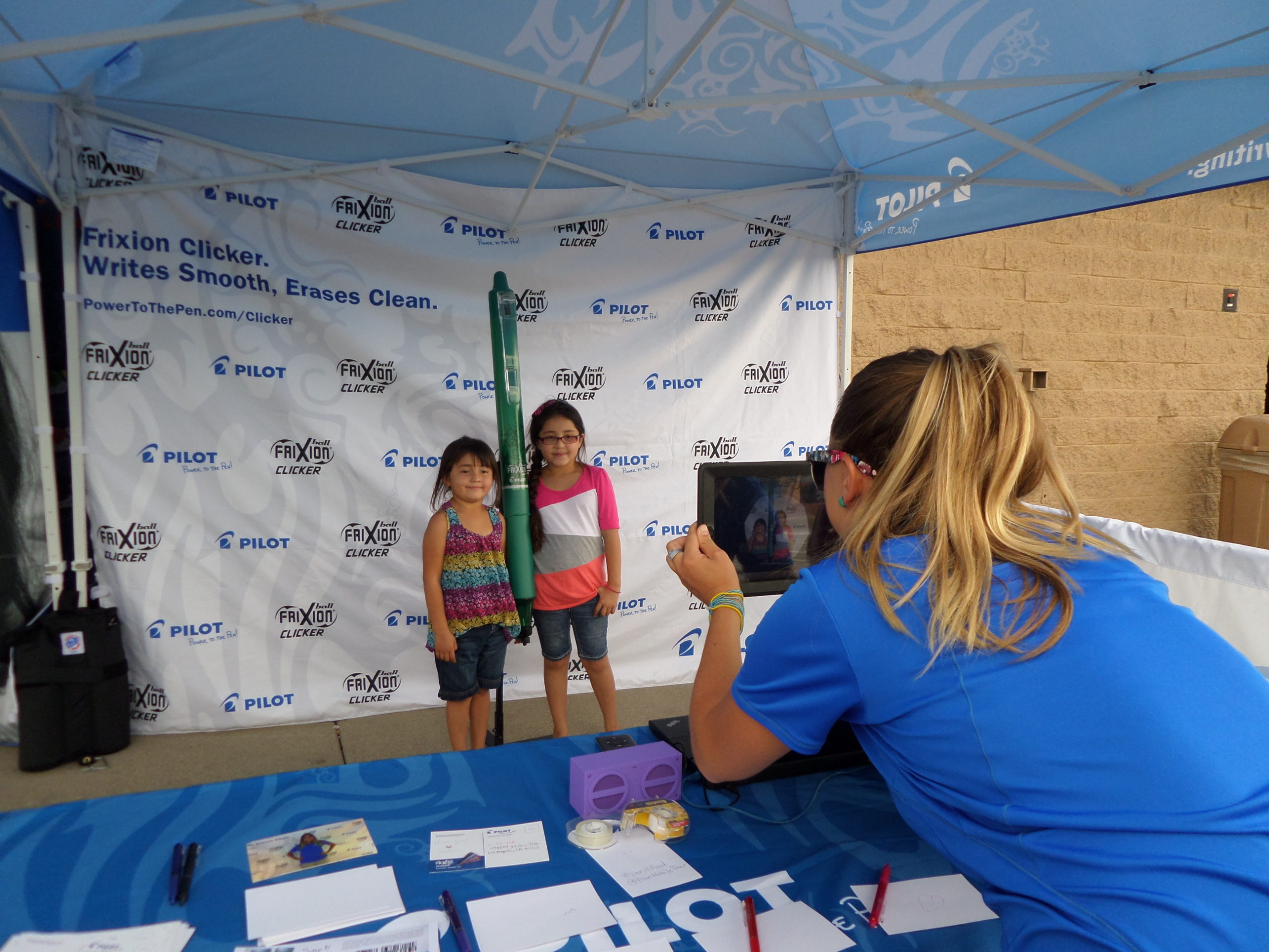 Two kids posing with a large Pilot pen